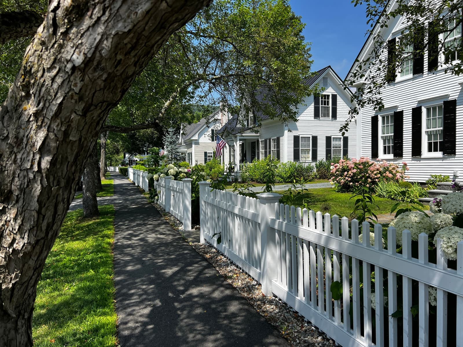 Sidewalk along white picket fences and clapboard houses, the kind of home movers in Cumberland, RI handle every week