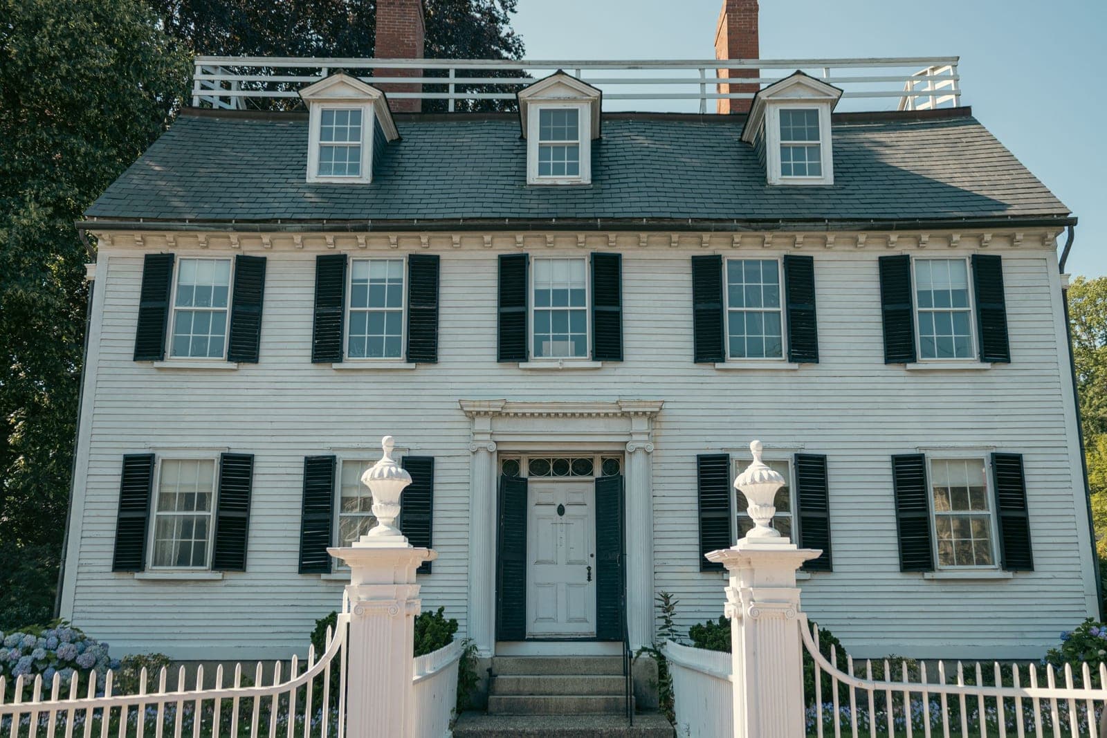 White colonial house with black shutters and a picket gate, the kind of home movers in East Greenwich, RI handle every week