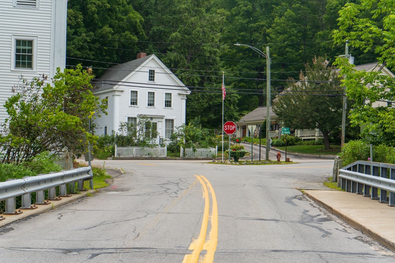 White clapboard houses at a quiet wooded intersection, the kind of home movers in Johnston, RI handle every week
